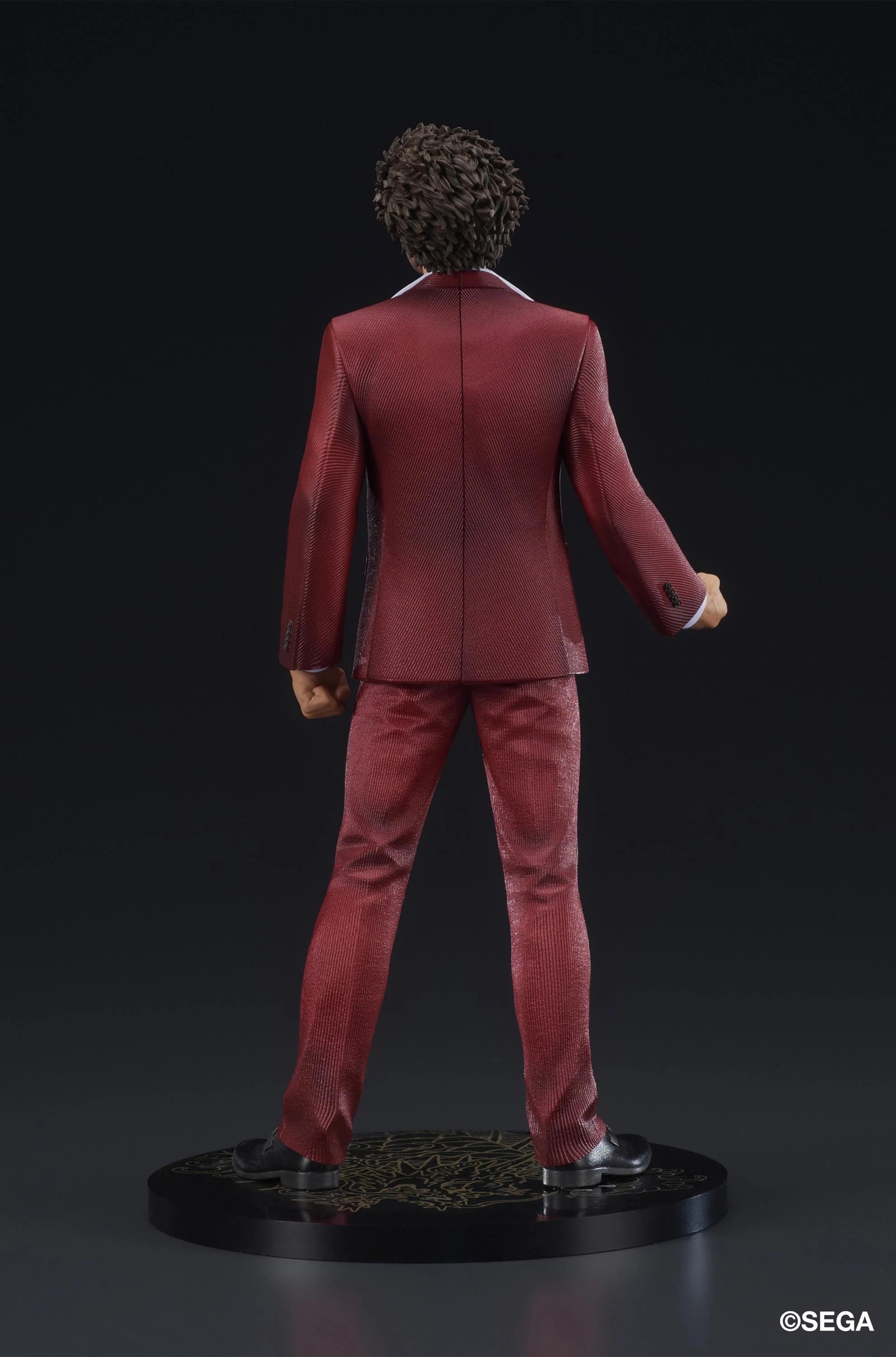 Rear view of the Ichiban Kasuga figure, showcasing the back of his red suit and the Dragon Fish design on the display base.