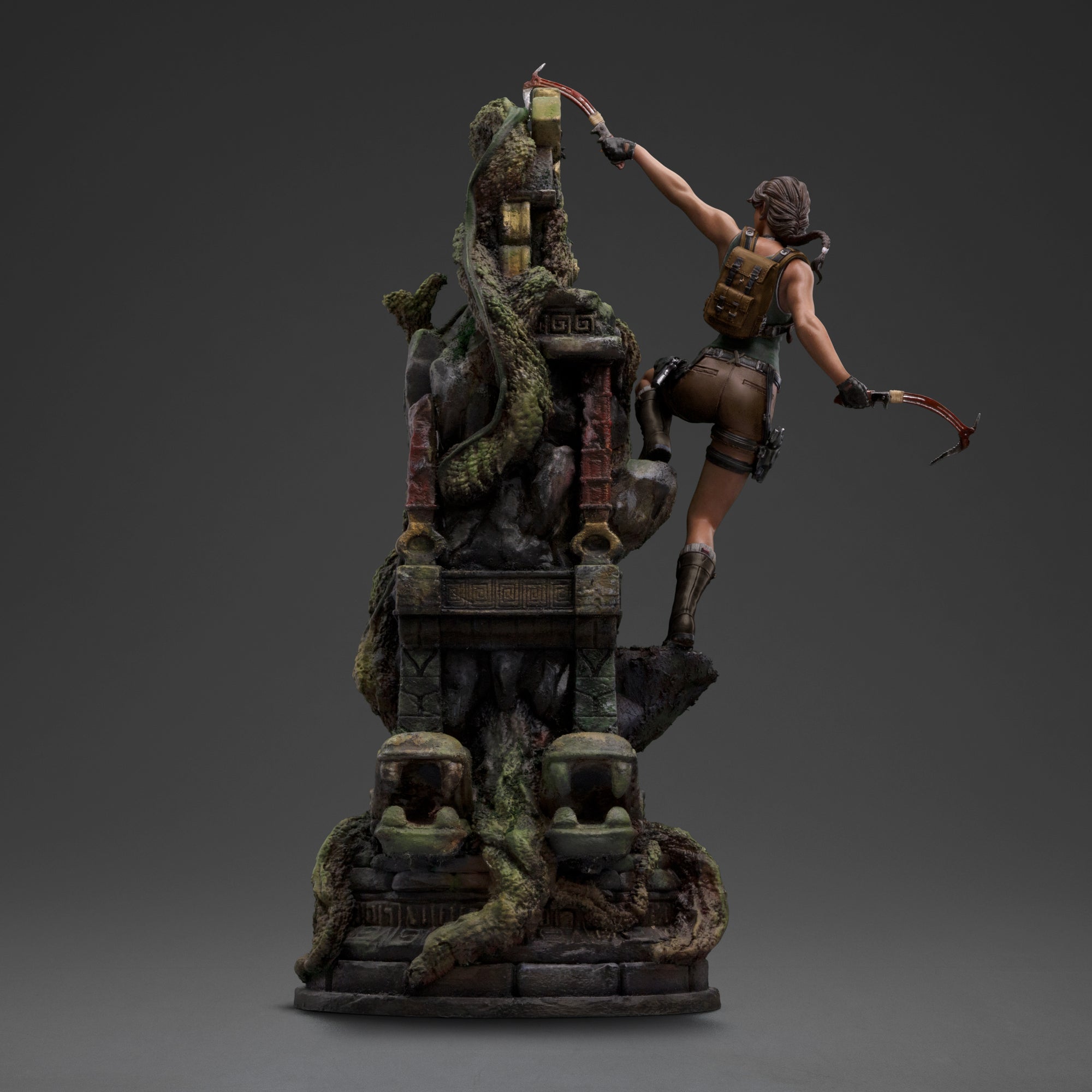 A back view of the Lara Croft statue, showing her in the climbing pose with her backpack and dual climbing axes.