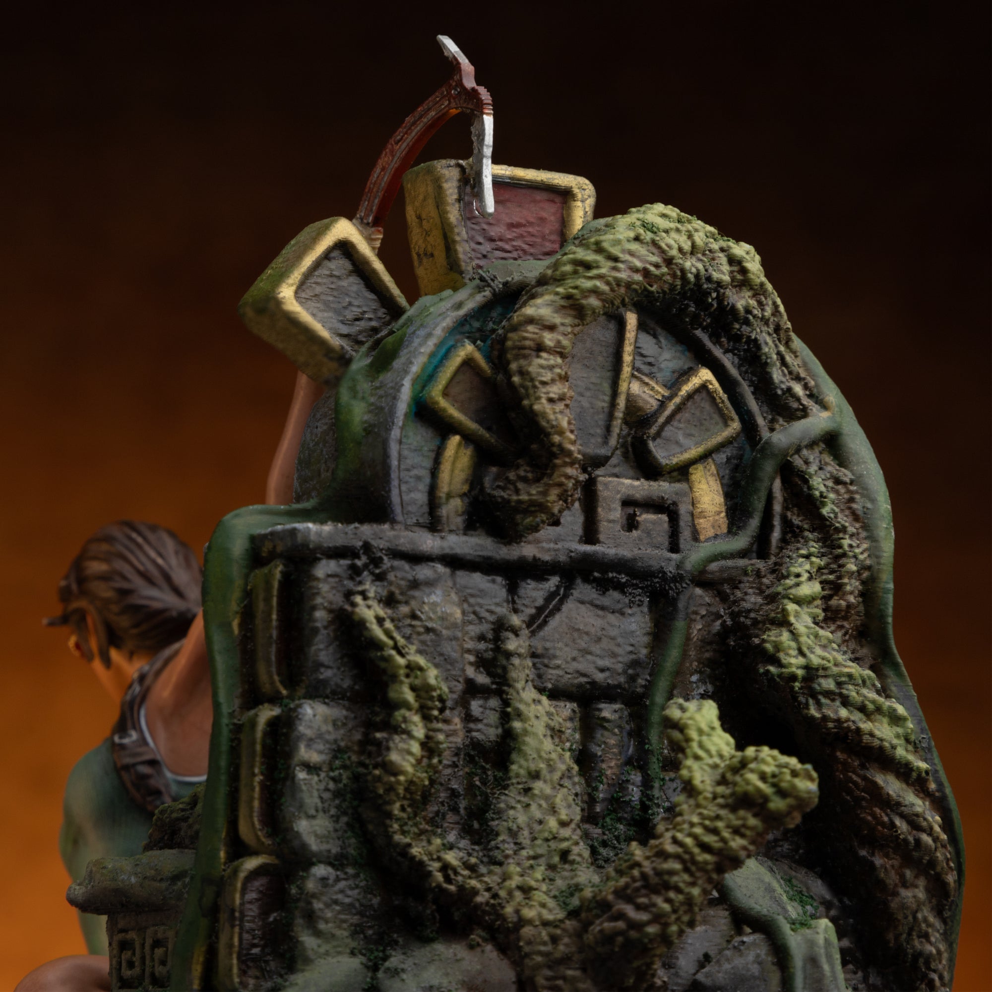 A close-up of the top portion of the ruined totem base from the Lara Croft statue, showing ancient symbols and overgrowth.