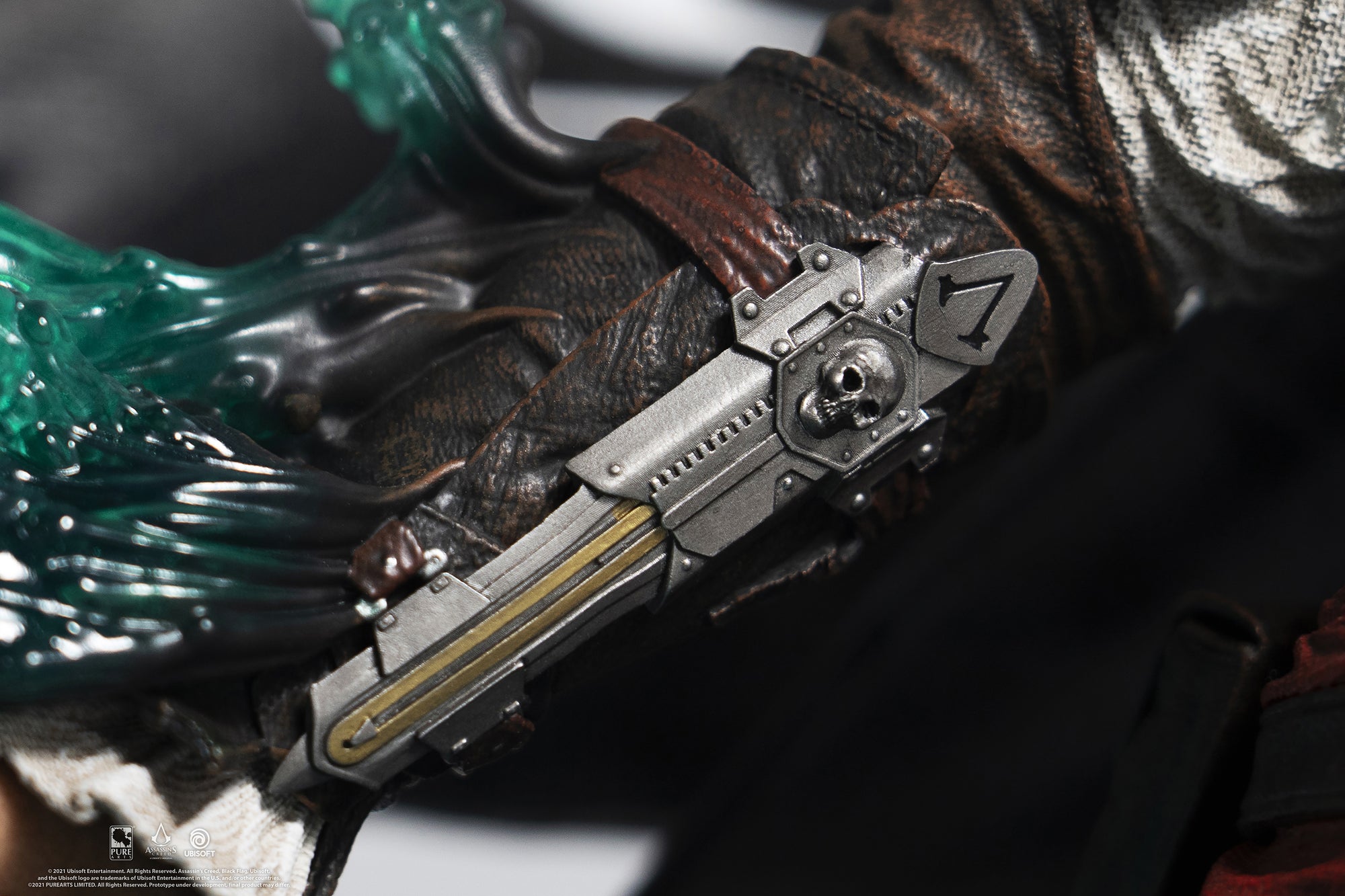 A detailed close-up of Edward Kenway’s forearm on the statue, showcasing his iconic hidden blade gauntlet with a skull and number seven emblem.