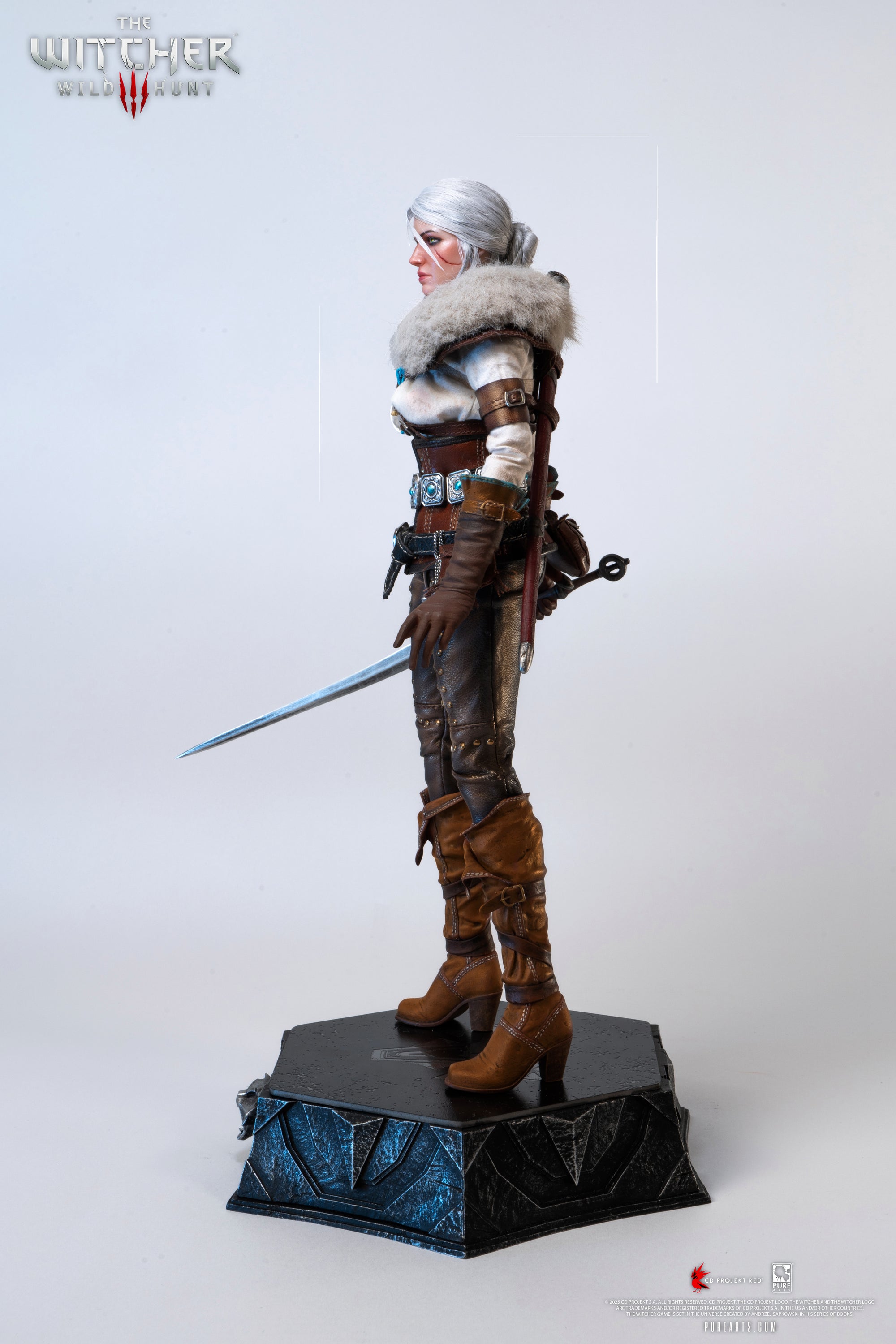Side profile of the Ciri figure wearing the fur mantle and drawing her metal sword.