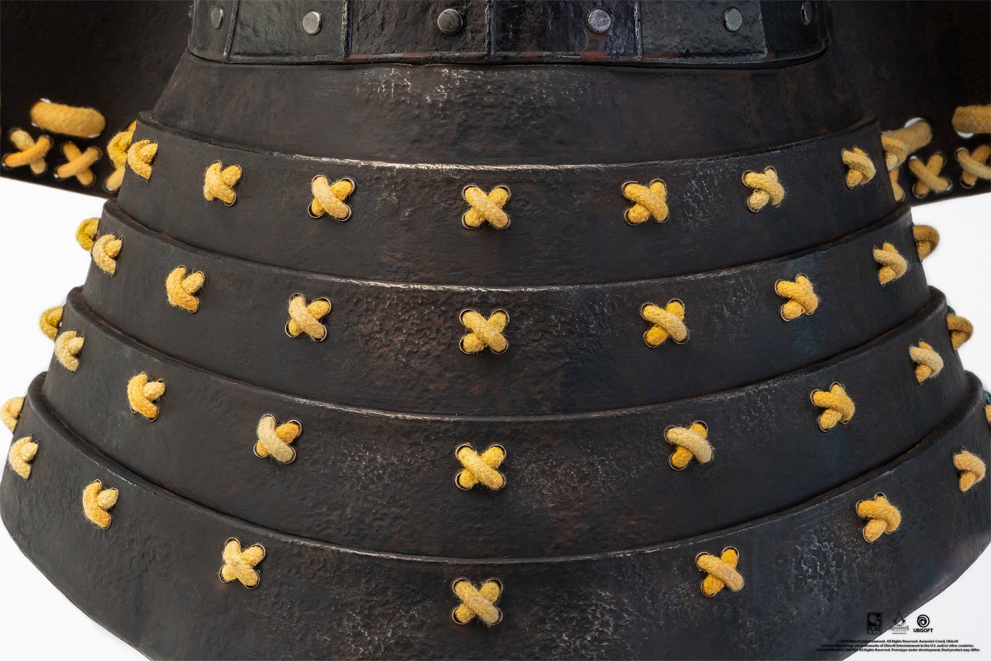 A close-up shot of the layered, textured black armor plates of the neck guard on the PureArts Yasuke helmet, tied together with yellow cords.