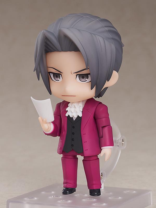 Miles Edgeworth Nendoroid figure behind wooden courtroom desk with angry faceplate and Japanese Hold It text plate.