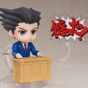 Phoenix Wright Nendoroid figure behind wooden courtroom desk with court document.