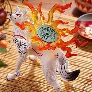 High-angle overhead shot of the Okami Amaterasu figure on a bamboo surface, accentuating the circular pattern on the green reflector and the spreading flame trail.
