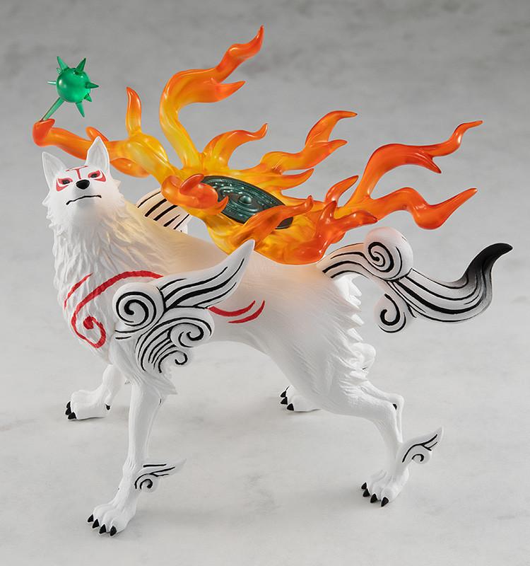 Elevated three-quarter side view of the Amaterasu plastic figure, showcasing the vibrant translucent orange flame effects and the green circular Divine Instrument reflector on her back.