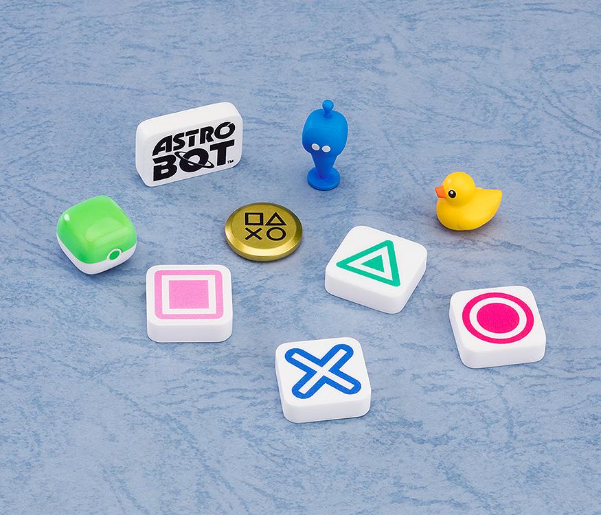 A group of random surprise accessories from the set, including PlayStation button symbols (Square, Triangle, Cross, Circle), a gold coin, a yellow rubber duck, and an Astro Bot logo piece.