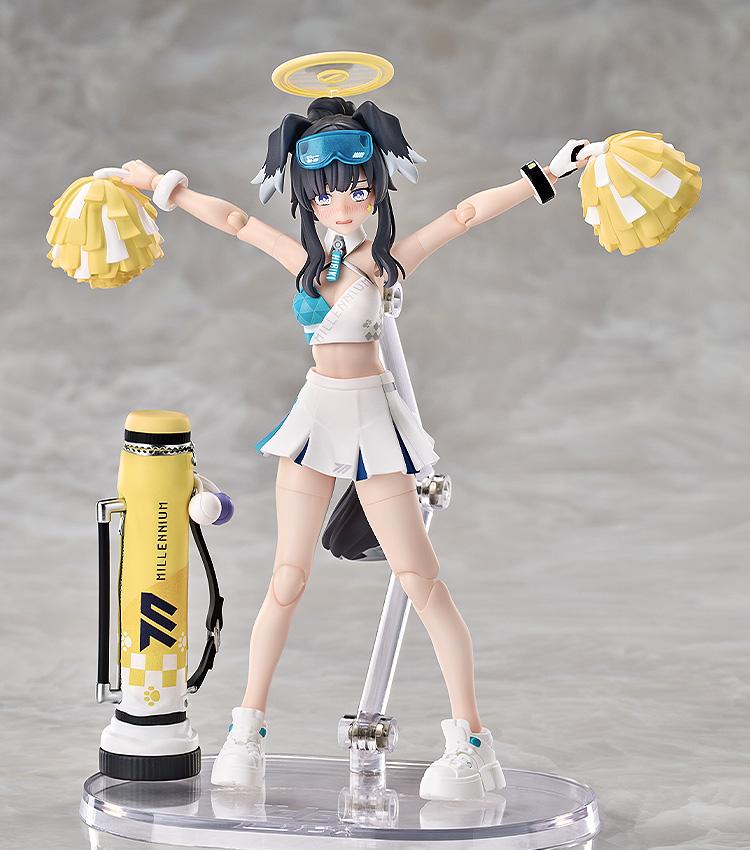 Hibiki with arms outstretched holding yellow pom-poms, posed next to her Millennium Science School mortar equipment.