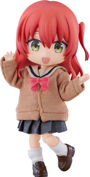Close-up front view of the Bocchi the Rock! Ikuyo Kita Nendoroid Doll figure with vibrant red hair, green eyes, and a cheerful open-mouthed smile, wearing a brown fabric uniform cardigan with a pink bow against a white background.