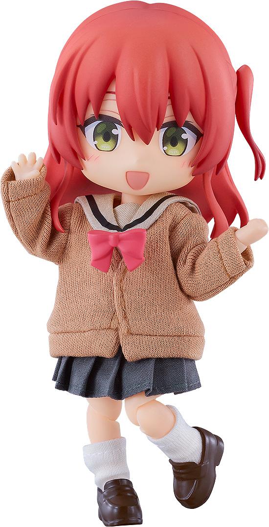 Close-up front view of the Bocchi the Rock! Ikuyo Kita Nendoroid Doll figure with vibrant red hair, green eyes, and a cheerful open-mouthed smile, wearing a brown fabric uniform cardigan with a pink bow against a white background.