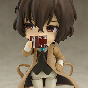 Nendoroid Osamu Dazai figure holding his book up to cover the lower half of his face, with a thoughtful/mischievous expression.