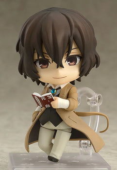 Nendoroid Osamu Dazai figure with the standard face, holding his book and wearing his tan trench coat and bandage-wrapped wrist.
