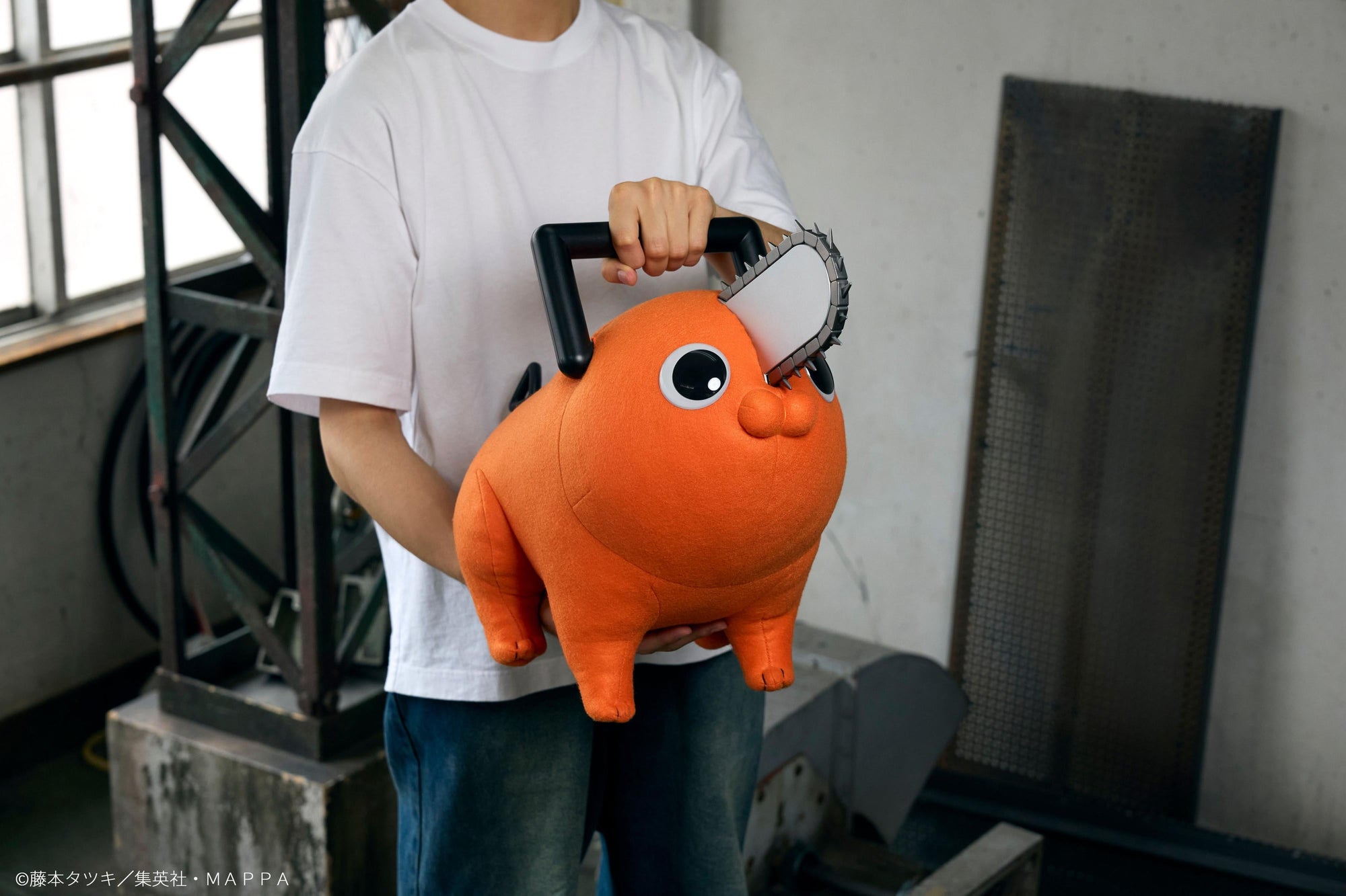 Person carrying the Pochita life-size plush doll using its top black chainsaw handle.