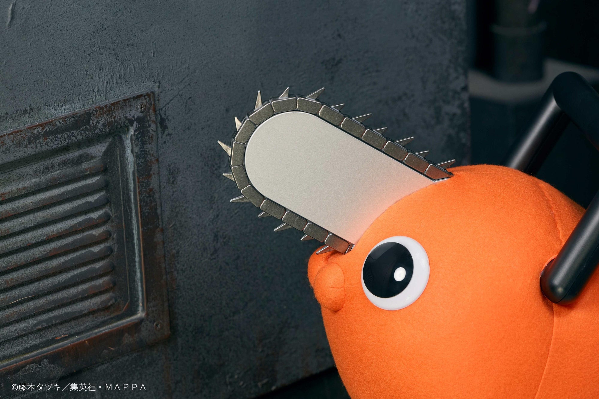 Close-up detail of Pochita's silver chainsaw blade, black handle, and glossy black eye.