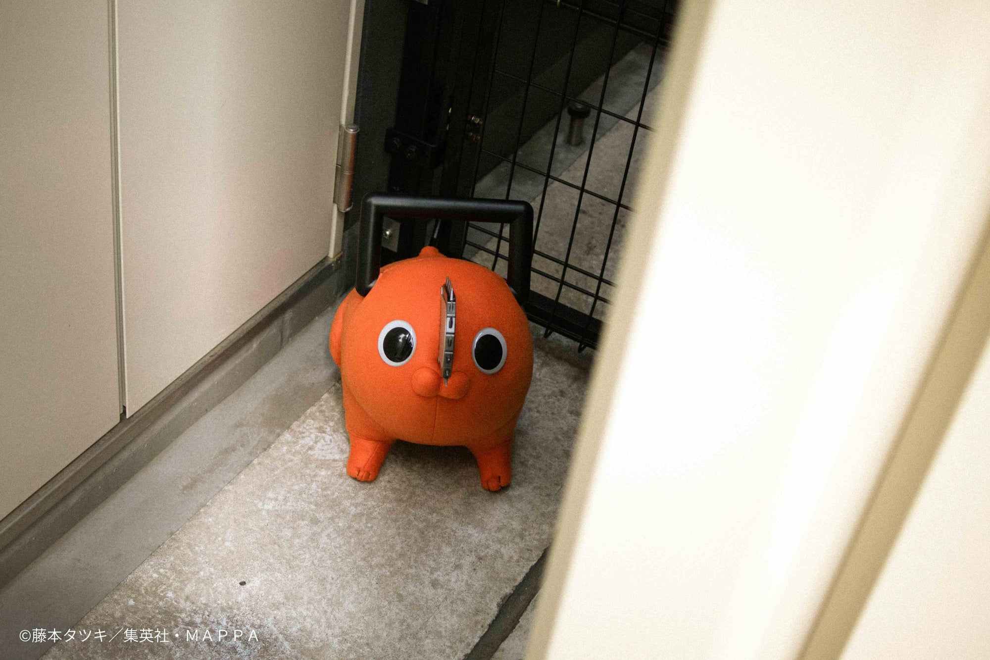 Pochita life-size plush doll standing in a doorway looking into a hallway.