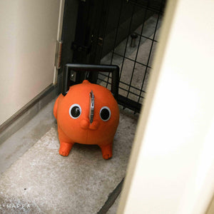 Pochita life-size plush doll standing in a doorway looking into a hallway.