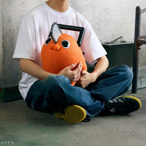 Person sitting cross-legged holding the 60cm Pochita life-size plush doll in their lap.