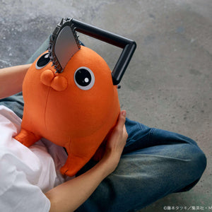 Overhead shot of a person cradling the Pochita life-size plush doll while seated on the floor.