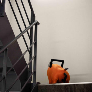 Rear view looking up at the Pochita life-size plush doll standing at the top of a staircase.