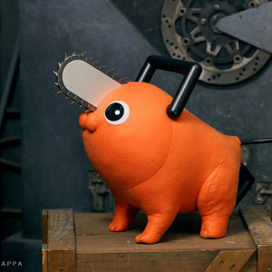 Pochita life-size plush doll standing on a wooden crate against an industrial gear backdrop.