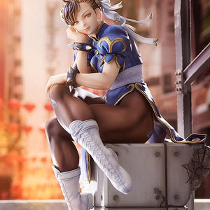 Full body shot of Chun-Li sitting on her base in a warm, outdoor street setting with red lanterns.