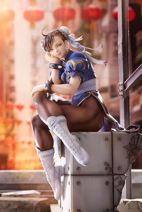 Full body shot of Chun-Li sitting on her base in a warm, outdoor street setting with red lanterns.