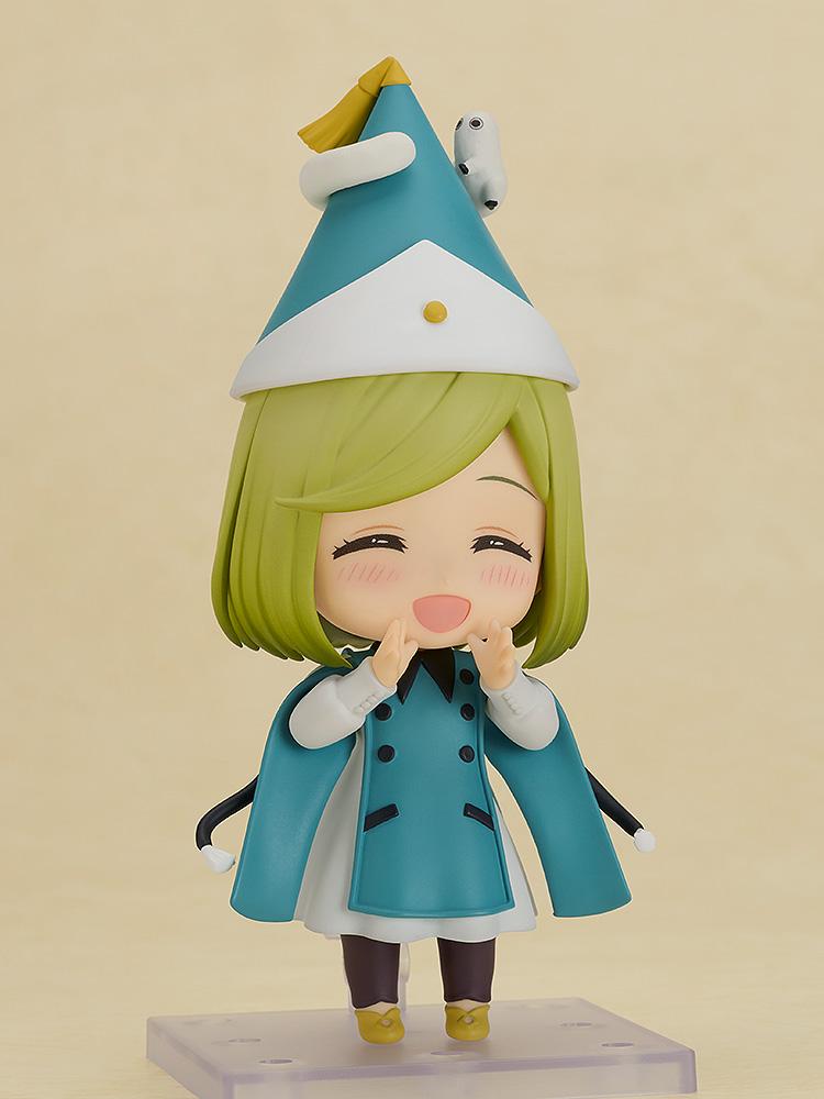 Front view of the Witch Hat Atelier Coco Nendoroid wearing a curled pointy hat with a tiny magical creature on top, showcasing her blushing, wide-mouthed smiling face plate.