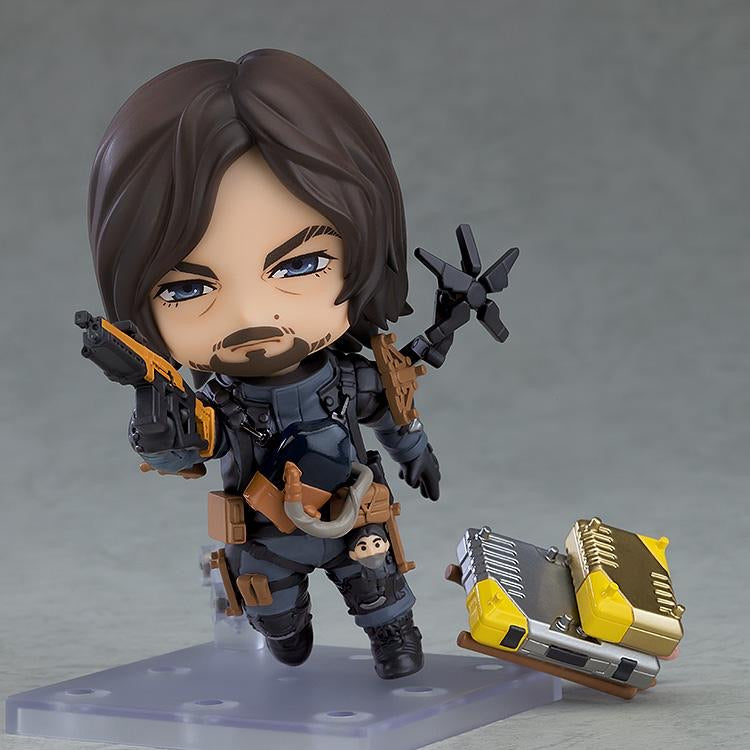 Nendoroid Sam figure holding the rifle accessory, posed next to stacked cargo containers.