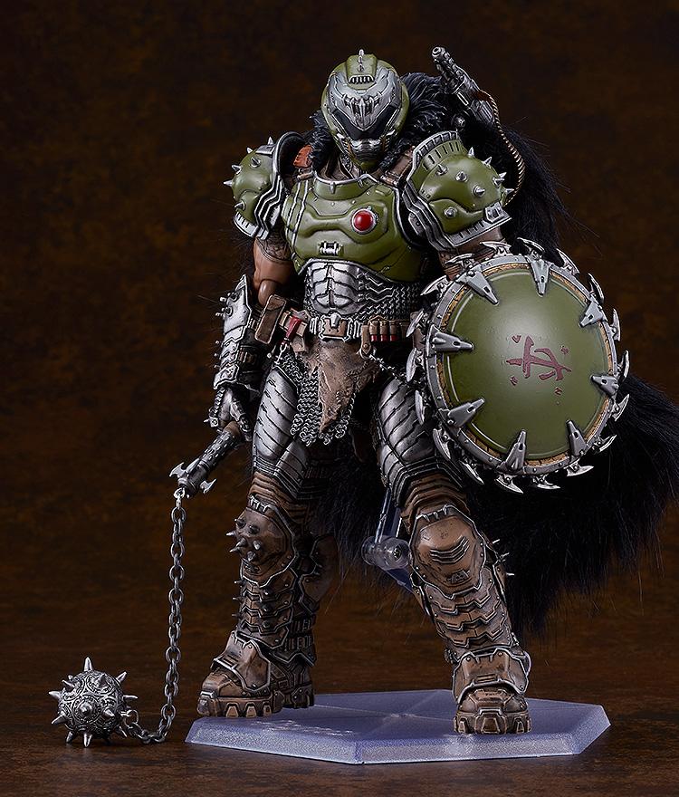 Full-body studio shot of the deluxe Doom Slayer figma standing on a clear display base, holding his spiked flail accessory against a dark brown background.