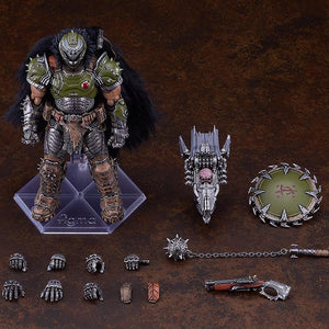 Overhead studio layout of the figma Doom Slayer DX Edition contents, showing the figure, interchangeable hands, cape attachments, super shotgun, spiked flail, chain shield, and skull crusher weapon.