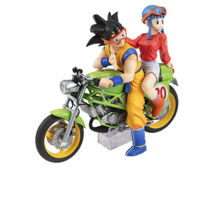Front-facing view of the Son Goku and Chi-Chi figure showing Goku looking back with orange goggles while seated on a bright green bike.