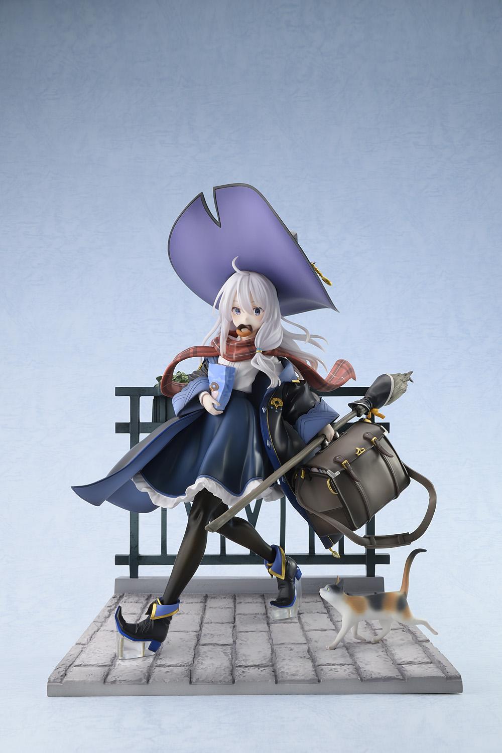 Full front view of the 1/7 scale Elaina Ash Witch DX figure wearing her signature black robe and pointed purple hat on a vignette cobblestone base against a soft blue background.
