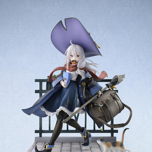 Full front view of the 1/7 scale Elaina Ash Witch DX figure wearing her signature black robe and pointed purple hat on a vignette cobblestone base against a soft blue background.