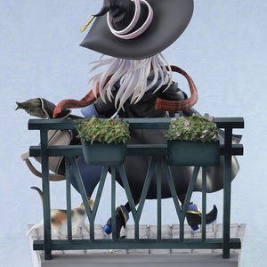 Rear view of the Elaina witch figure highlighting her long flowing silver hair, black pointed hat, and the vignette balcony railing base decorated with flower planters.