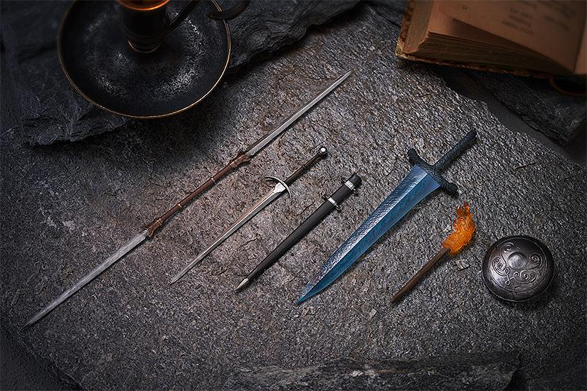 Top-down flat lay view of the detailed figma weapon accessories, including the Twinblade, bastard sword with sheath, Dark Moon Greatsword, flaming torch, and roundshield arranged on a dark stone slab.