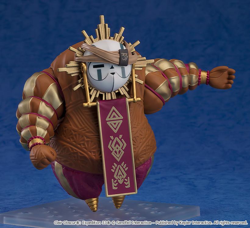 Front three-quarter shot of the Esquie Nendoroid figure wearing a tan fabric headband with a black number 33 emblem over its mask, pointing out with one hand.