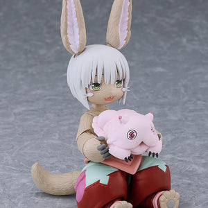 Seated figma Nanachi figure without her hat, gently holding the small pink Mitty figure in her lap.