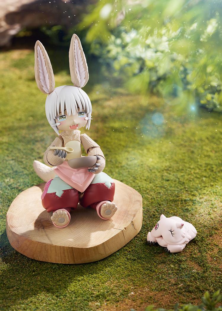 Scenic outdoor diorama shot of the figma Nanachi figure sitting on a wood slice eating from a bowl with her blissful expression.