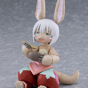 Seated figma Nanachi figure without her helmet hat, featuring a teary blissful face plate while holding a spoon and a bowl of deep-fried gankimasu.