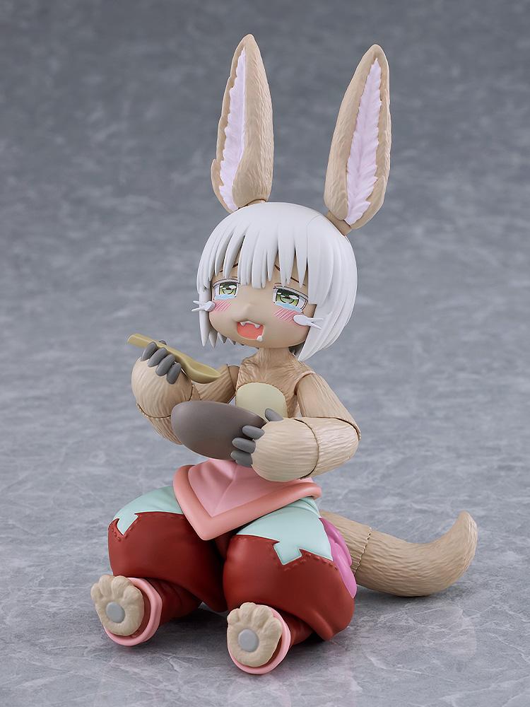 Seated figma Nanachi figure without her helmet hat, featuring a teary blissful face plate while holding a spoon and a bowl of deep-fried gankimasu.