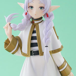 Close-up studio shot of the Frieren figure showing her gentle green eyes, red dangling earrings, and her hand lifting the tip of her braided hair.