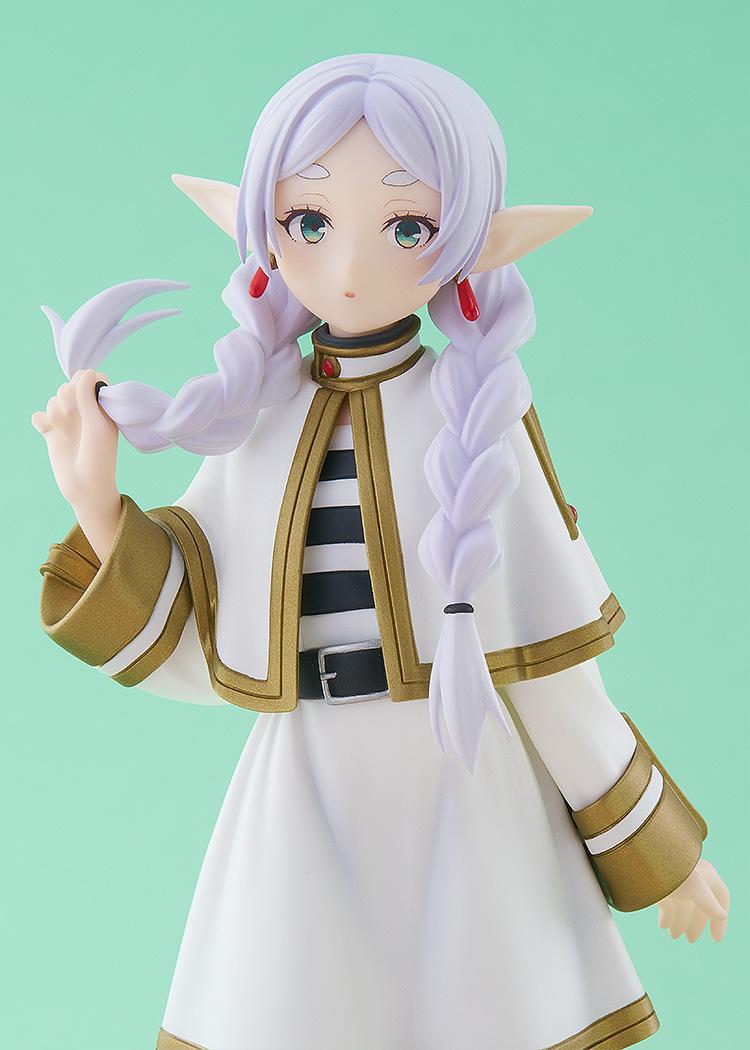 Close-up studio shot of the Frieren figure showing her gentle green eyes, red dangling earrings, and her hand lifting the tip of her braided hair.