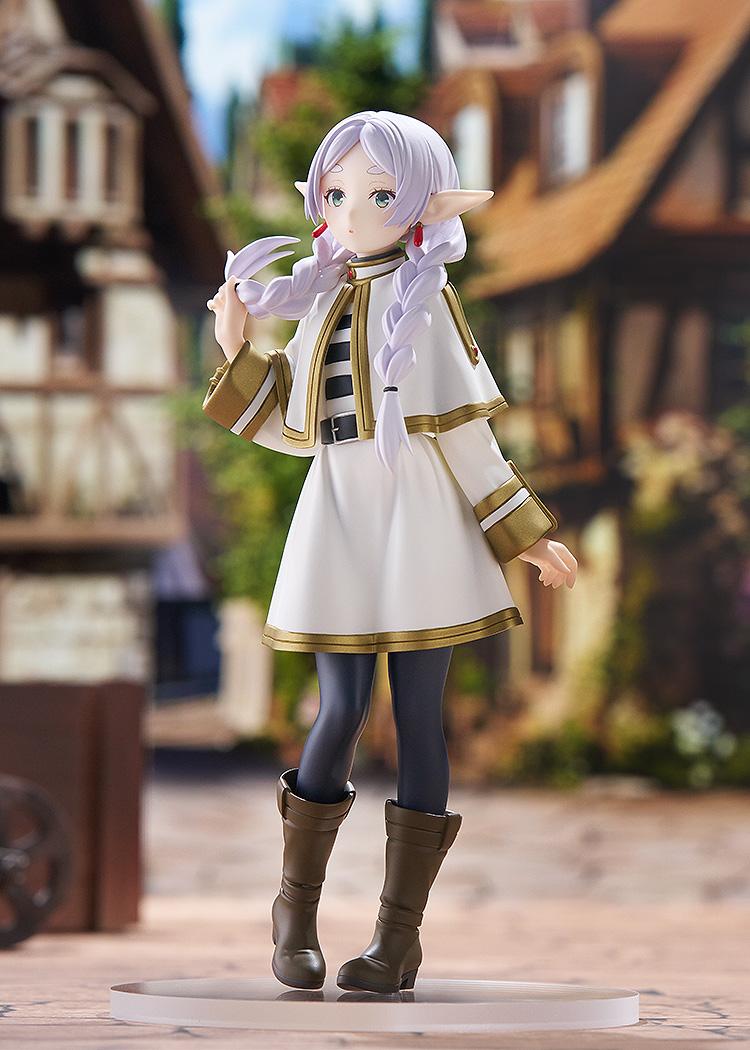 Full-body three-quarter angle of the Frieren elven mage figure posed within a detailed medieval fantasy town layout under a blue sky.