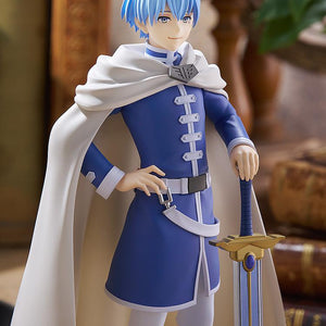Medium shot of the Himmel hero figure in a rustic study setting, capturing the detailed painting on his tunic, gold armor trim, and sword hilt.