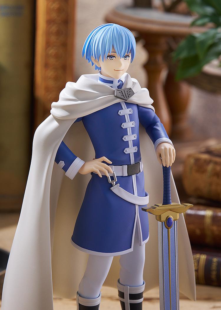 Medium shot of the Himmel hero figure in a rustic study setting, capturing the detailed painting on his tunic, gold armor trim, and sword hilt.