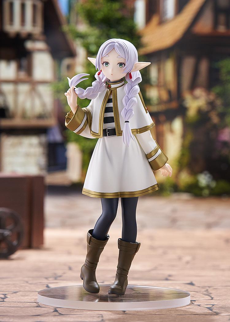 Full-body showcase of the Frieren Braids version figure standing on a stone-paved floor in a miniature medieval village setting.