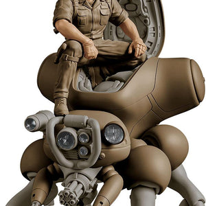 Close-up studio product shot of the 1/20 scale PLAMAX Batou figure with cybernetic eyes sitting in the open cockpit hatch of a khaki-brown Fuchikoma spider tank against a white background.