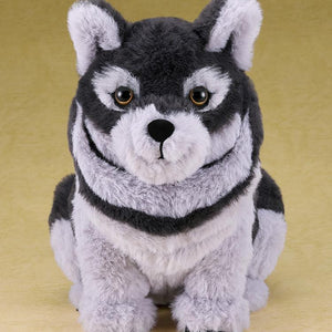 Full-body studio shot of the sitting wolf plushie, a soft polyester companion from the Ghost of Yotei video game.