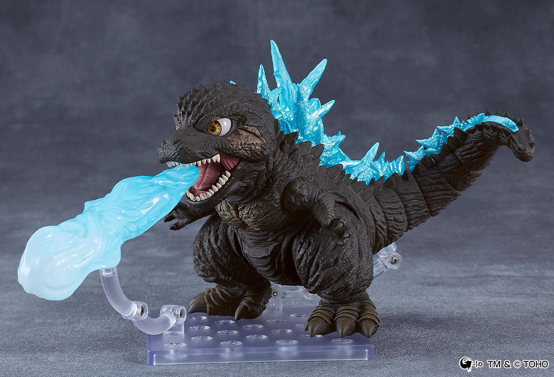 Action pose of the Godzilla 2023 Nendoroid figure blasting a blue atomic breath ray effect piece attached to a clear stand.