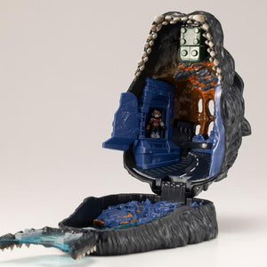 Interior of opened Godzilla pocket playset showing hinged building door and hidden pilot figure.
